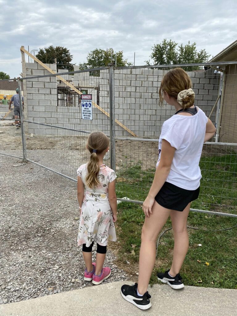 Two girls watching the workers build the addition
